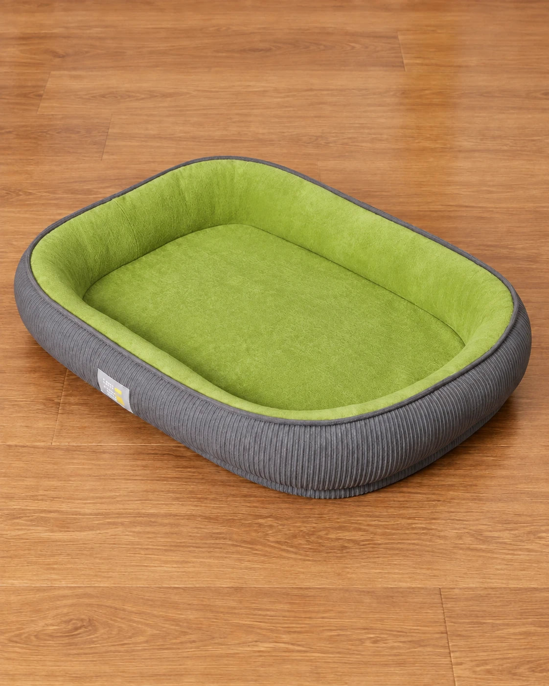 Empty green After-Walk Comfort Dog Bed with grey ribbed sides on a brown wooden floor
